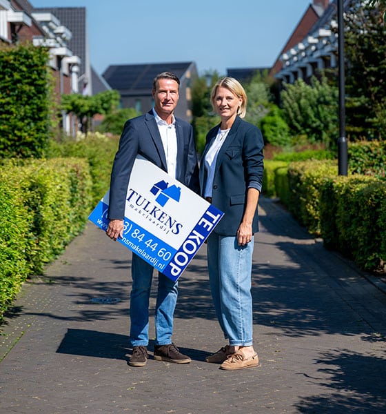 makelaars op pad met verkoopbord onder de arm