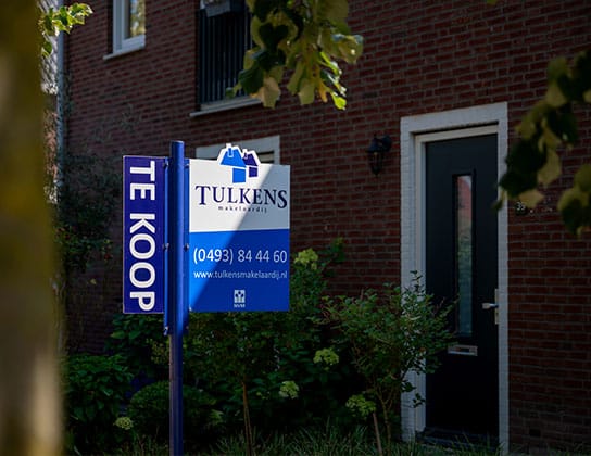 verkoopbord in tuin bij moderne woning